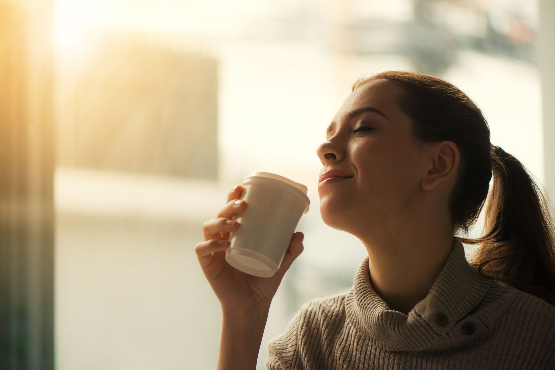 Frau geniesst eine Tasse Kaffee im Morgenlicht